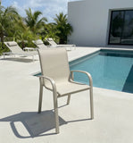 Light gray aluminum outdoor armchair with curved armrests and mesh seat/back
